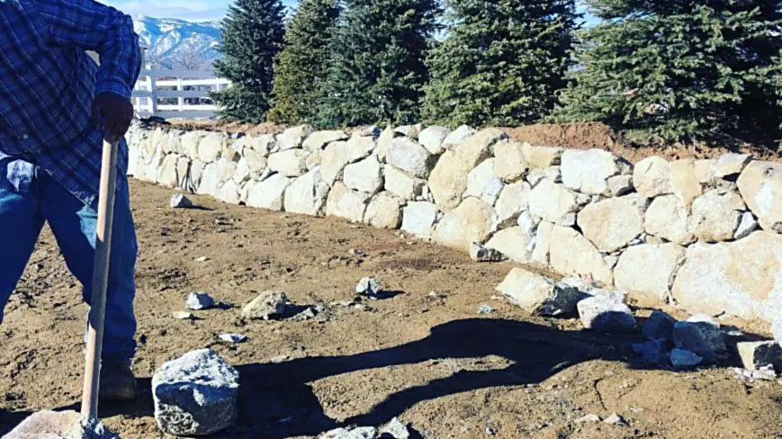New trees planted alongside a finished boulder retaining wall