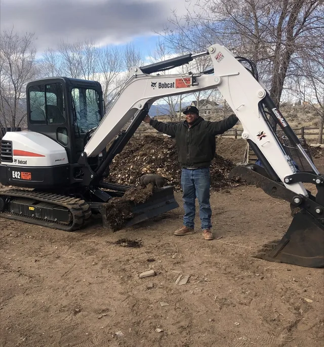 Eduardo, owner of Grass Reaper LLC, on a job site with his excavator
