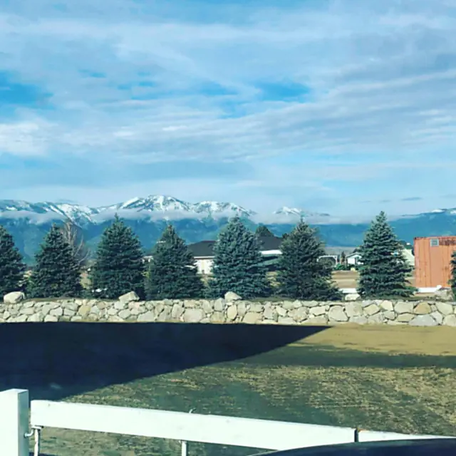 Established green lawn beside a boulder wall with the Sierra Nevada behind