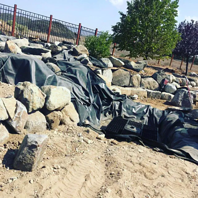 Pondless water feature under construction with basin and boulder placement